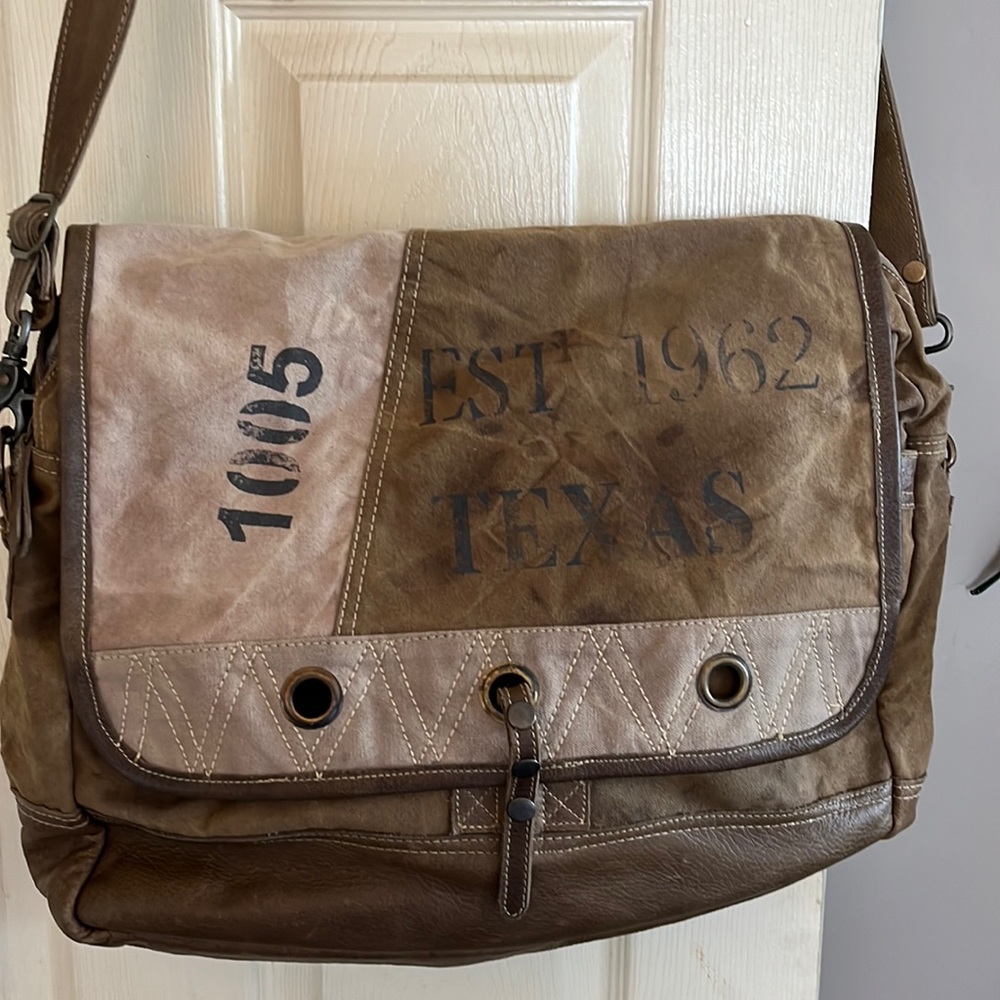 Intentionally distressed tote with multiple pockets and a detachable strap.